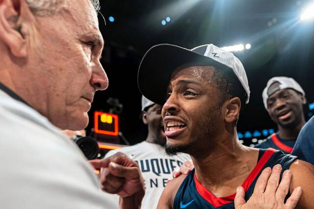 Duquesne’s Kareem Rozier congratulates coach Keith Dambrot after the Dukes beat VCU in the Atlantic 10 Tournament championship game Sunday in New York.