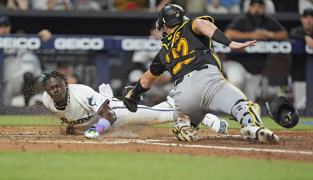 Miami Marlins’ Jazz Chisholm Jr. (left) scores as Pirates catcher Henry Davis attempts the tag in the third inning of the game Thursday in Miami.