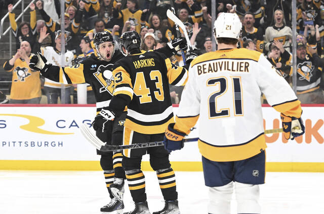 The Penguins’ Jansen Harkins celebrates with Emil Bemstrom on Monday after Bemstrom’s goal against the Predators in the third period at PPG Paints Arena.