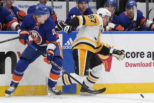 The Islanders’ Simon Holmstrom (left) and Pittsburgh’s Sidney Crosby scuffle for the puck during the first period Wednesday.