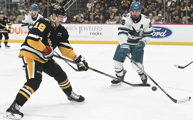 The Penguins’ Reilly Smith wields a third-period shot past the Sharks’ Mario Ferraro on March 14 , 2024, at PPG Paints Arena.