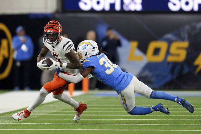Cincinnati Bengals wide receiver Tee Higgins is tackled by Los Angeles Chargers cornerback Ja’Sir Taylor during a Nov. 17 game. Higgins returned from a three-game injury absence that day, and quarterback Joe Burrow’s efficiency improved.