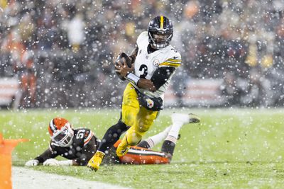 Pittsburgh Steelers quarterback Russell Wilson fights off a Cleveland Browns defender during a snowy 2024 regular season outing from Huntington Bank Field.