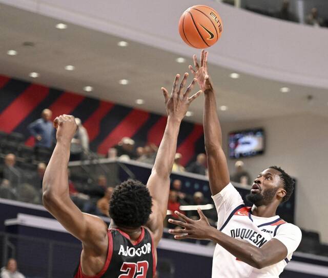 Duquesne’s David Dixon hits a shot over Saint Joseph’s Justice Ajogbor last season.