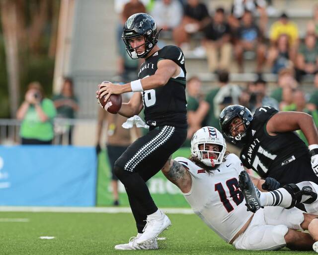 Duquesne defensive lineman A.J. Ackerman (16) nearly pulls down Hawaii quarterback Joey Yellen (18) during the first half of an NCAA college football game Saturday, Sept. 17, 2022, in Honolulu.
