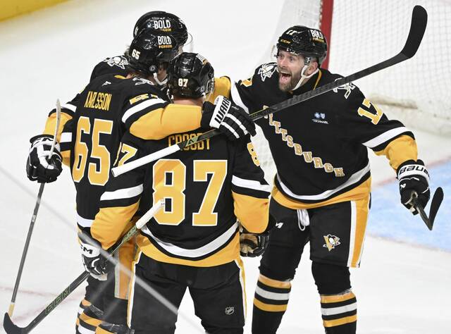 The Penguins’ Ville Koivunen, Sidney Crosby and Bryan Rust celebrate with Erik Karlsson after Karlsson scored his 200th NHL goal against the Black Hawks in the second period April 8, 2025 at PPG Paints Arena.