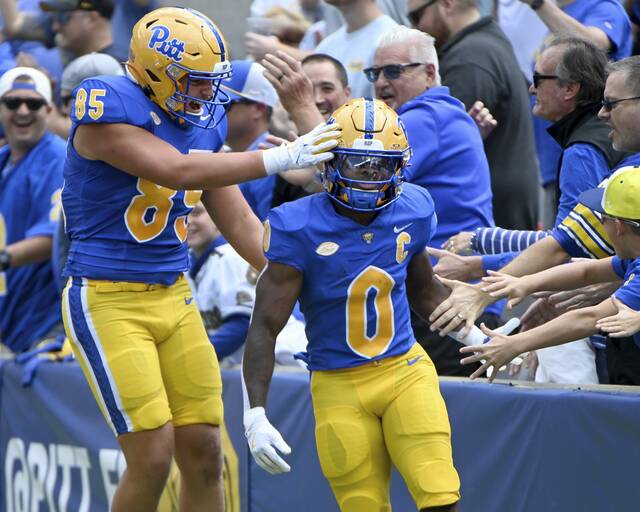 Pitt’s Desmond Reid celebrates with tight end Josh Altsman and fans after returning a punt for a touchdown during the first quarter against Duquesne on Saturday at Acrisure Stadium.