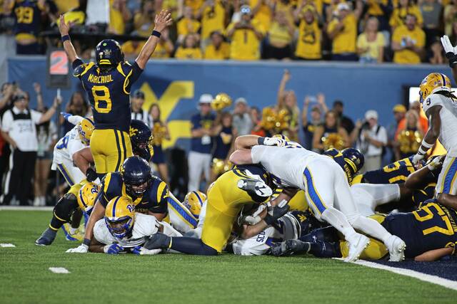 West Virginia quarterback Nicco Marchiol (8) signals a touchdown during overtime against Pitt on Saturday in Morgantown, W.Va.
