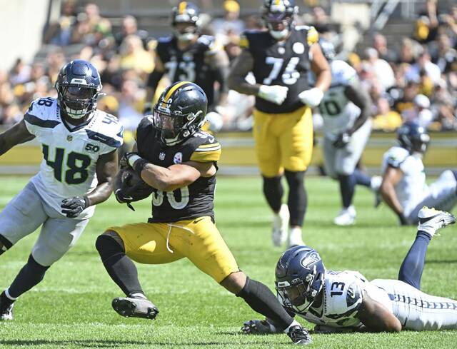 Steelers running back Jaylen Warren with gets away from the Seahawks’ Ernest Jones IV on a 65-yard catch and run Sunday.