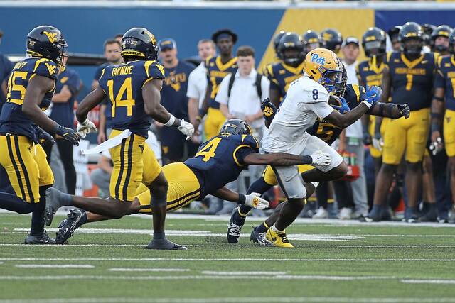 Pitt running back Juelz Goff (8) is defended by West Virginia safety Jordan Walker (4) during the second half of an NCAA college football game Saturday, Sept. 13, 2025, in Morgantown, W.Va.