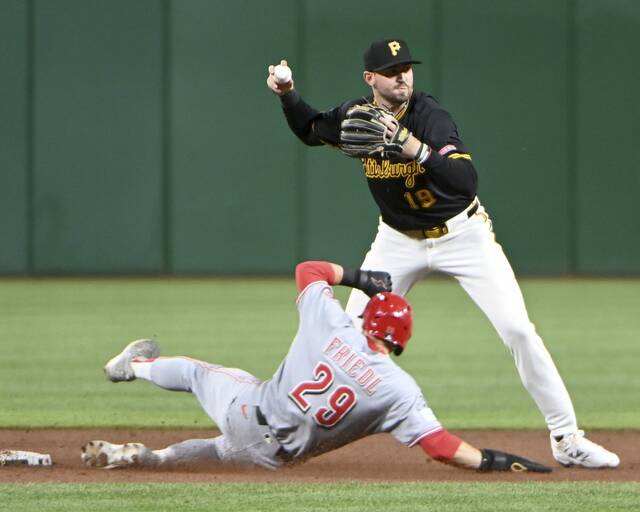 Pirates shortstop Jared Triolo turns a double play over the Reds’ TJ Friedl during the ninth inning on Tuesday, May 20, 2025, at PNC Park.