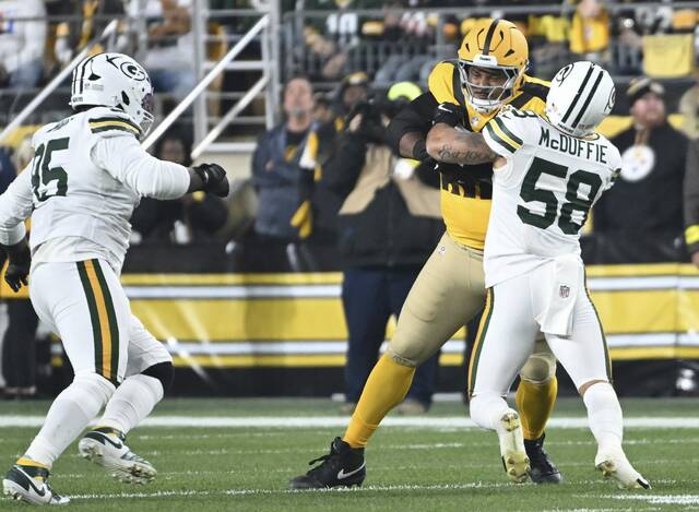 Pittsburgh Steelers offensive lineman Spencer Anderson runs with the ball after a catch as an eligible receiver early during Sunday’s game against the Green Bay Packers. Linebacker Isaiah McDuffie (No. 58) needs help from defensive tackle Devonte Wyatt (left) to bring him down.