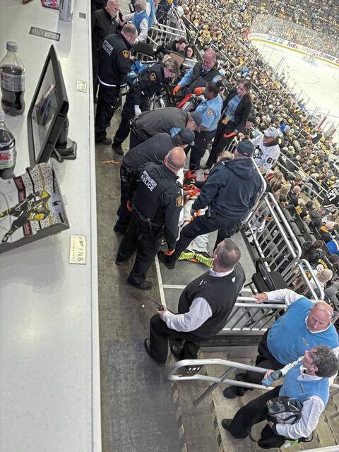 Pittsburgh emergency medical services workers treat a fan who fell from the stands Monday night at PPG Paints Arena.