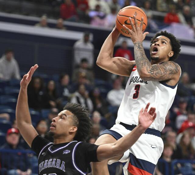 Duquesne’s Jimmie Williams scores over Niagara’s Brian Griffith in the second half Monday at UPMC Cooper Fieldhouse.