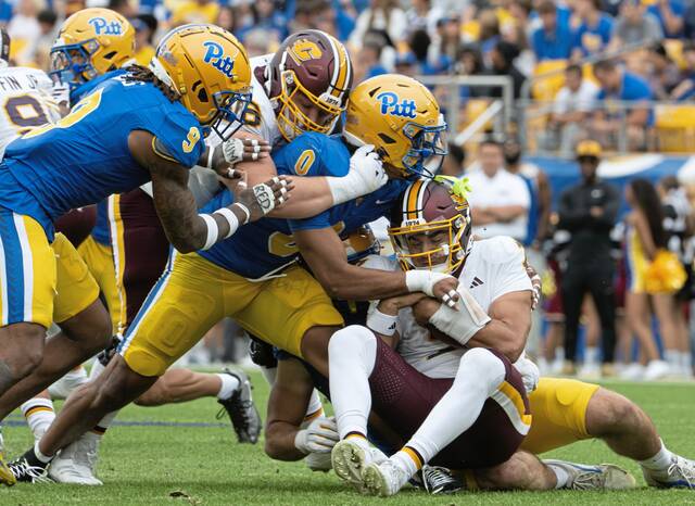 Central Michigan quarterback Angel Flores is swarmed by Pitt’s Braylan Lovelace (0) and Kyle Louis (9) last month.