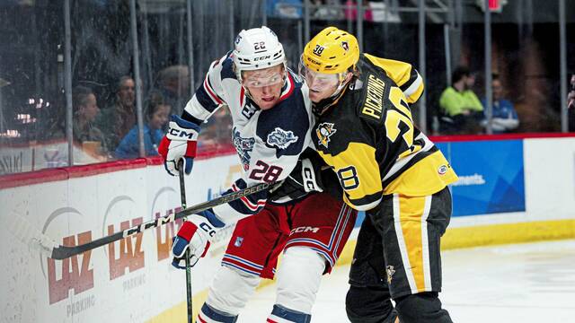 Hartford Wolf Pack forward Dylan Roobroeck and Wilkes-Barre/Scranton Penguins defensemen Owen Pickering battle along the boards during a game at PeoplesBank Arena in Hartford, Conn. on Nov. 21, 2025. The Wolf Pack won, 5-2.