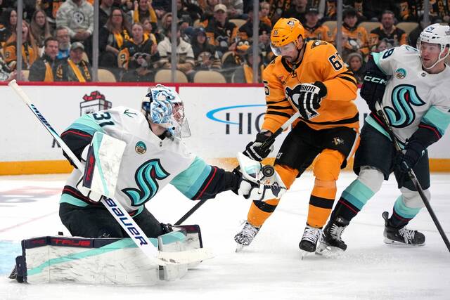 Kraken goaltender Philipp Grubauer (31) gloves the puck before the Penguins’ Erik Karlsson (65) can get his stick on it with Vince Dunn (29) defending during the second period Saturday.