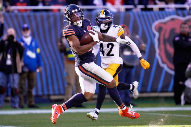 Chicago Bears wide receiver DJ Moore (left) backs into the end zone after taking a pass from quarterback Caleb Williams for a touchdown with Steelers cornerback James Pierre defending.
