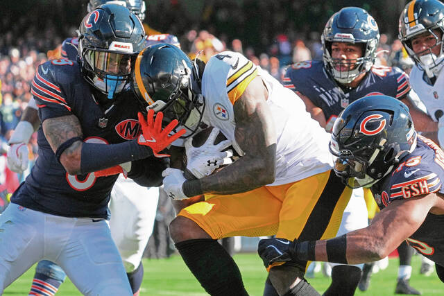 Pittsburgh Steelers wide receiver DK Metcalf rushes for a touchdown with Chicago Bears safety Jaquan Brisker, left and Amen Ogbongbemiga, right, defending during Sunday’s game. Metcalf suffered an ankle injury during the game and did not practice Wednesday.