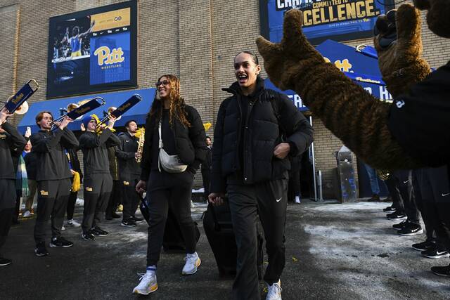 Pitt volleyball players Bre Kelley (left) and Olivia Babcock react to the band and fans as they leave the Fitzgerald Field House to board the bus to head to the semifinals of the NCAA Tournament on Tuesday, Dec. 16, 2025. (Kristina Serafini | TribLive)